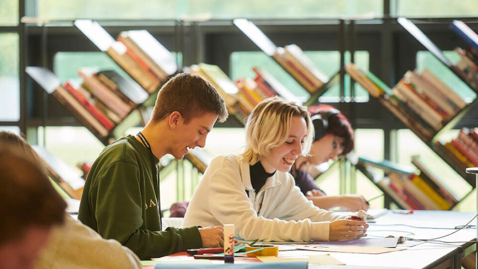 Students sitting at a table creating coursework